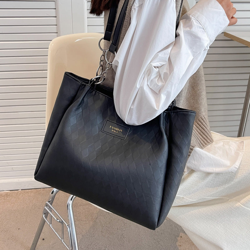 Sac à main femme noir motif losange avec chaîne, style chic, porté épaule ou main, idéal pour le shopping ou un usage quotidien.